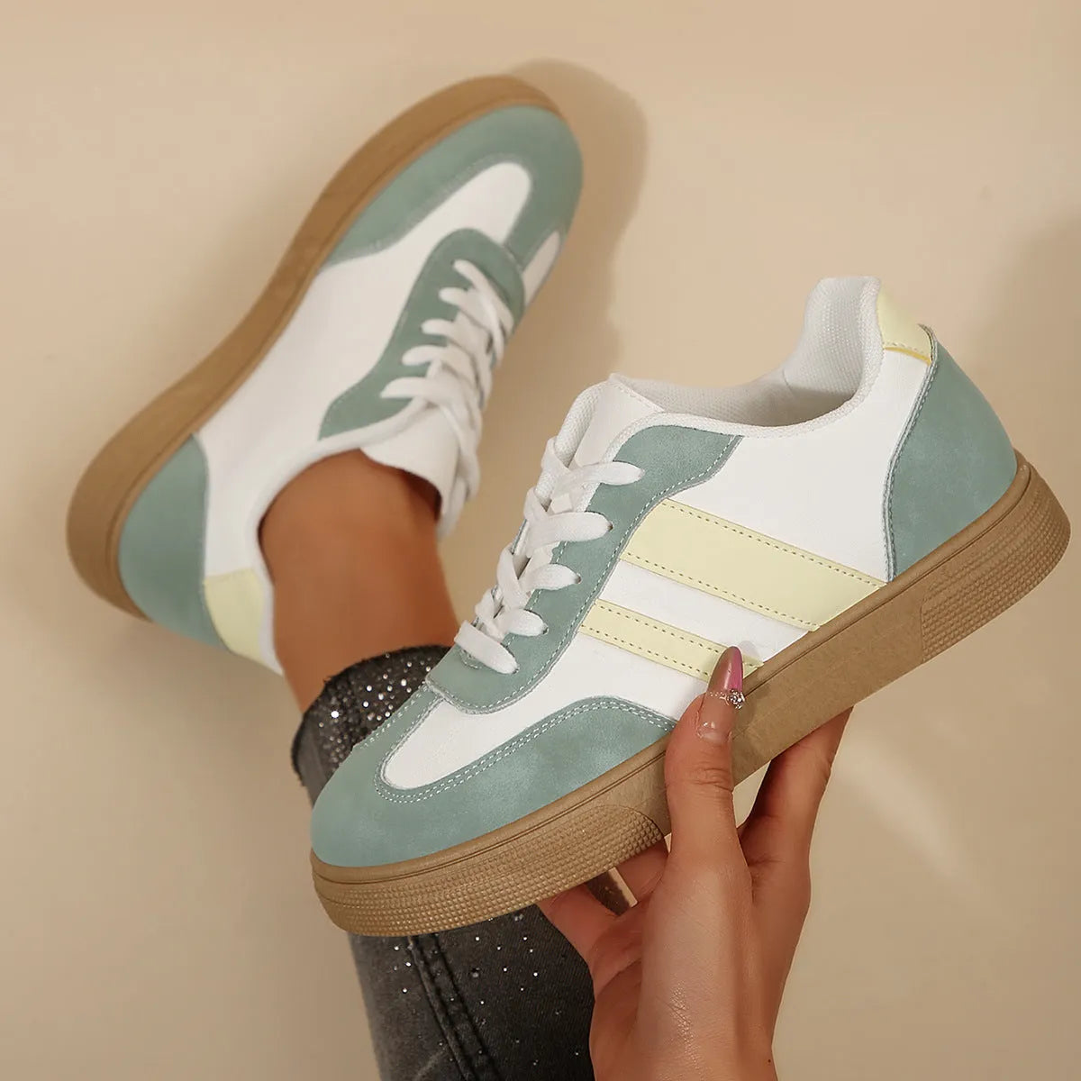 Green women's retro low-top trainers with cross-strap detail and round toe on a white background.