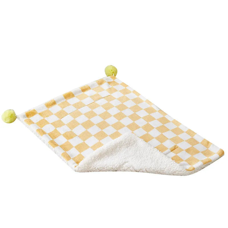 Green plaid pattern soft fleece pet blanket with fur ball decoration on a sofa