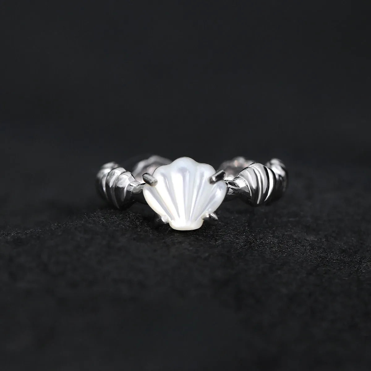 Adjustable silver ring featuring a carved shell and tiger eye stone design in a choice of finishes.