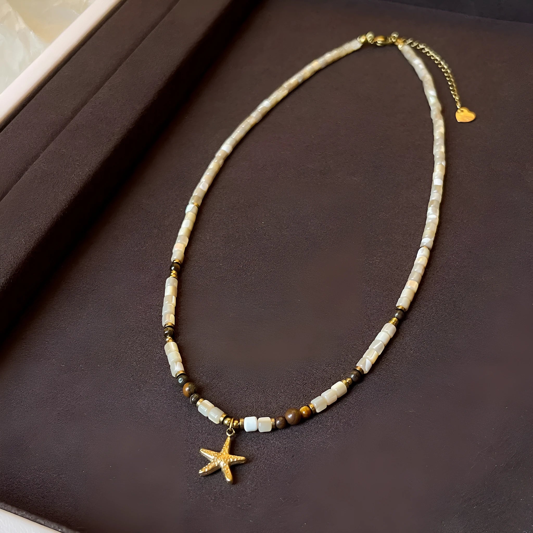 Close view of titanium steel starfish pendant necklace with natural shell and tigereye bead on a woman, Maillard colour, 41-50cm chain