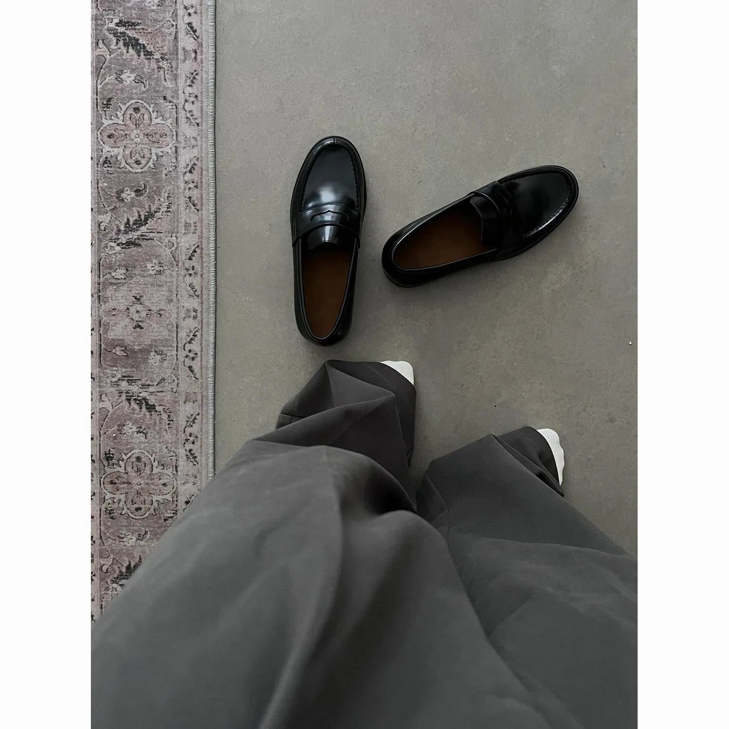 Men's black British-style slip-on leather loafers with stitched seams and vulcanised rubber sole on a plain background