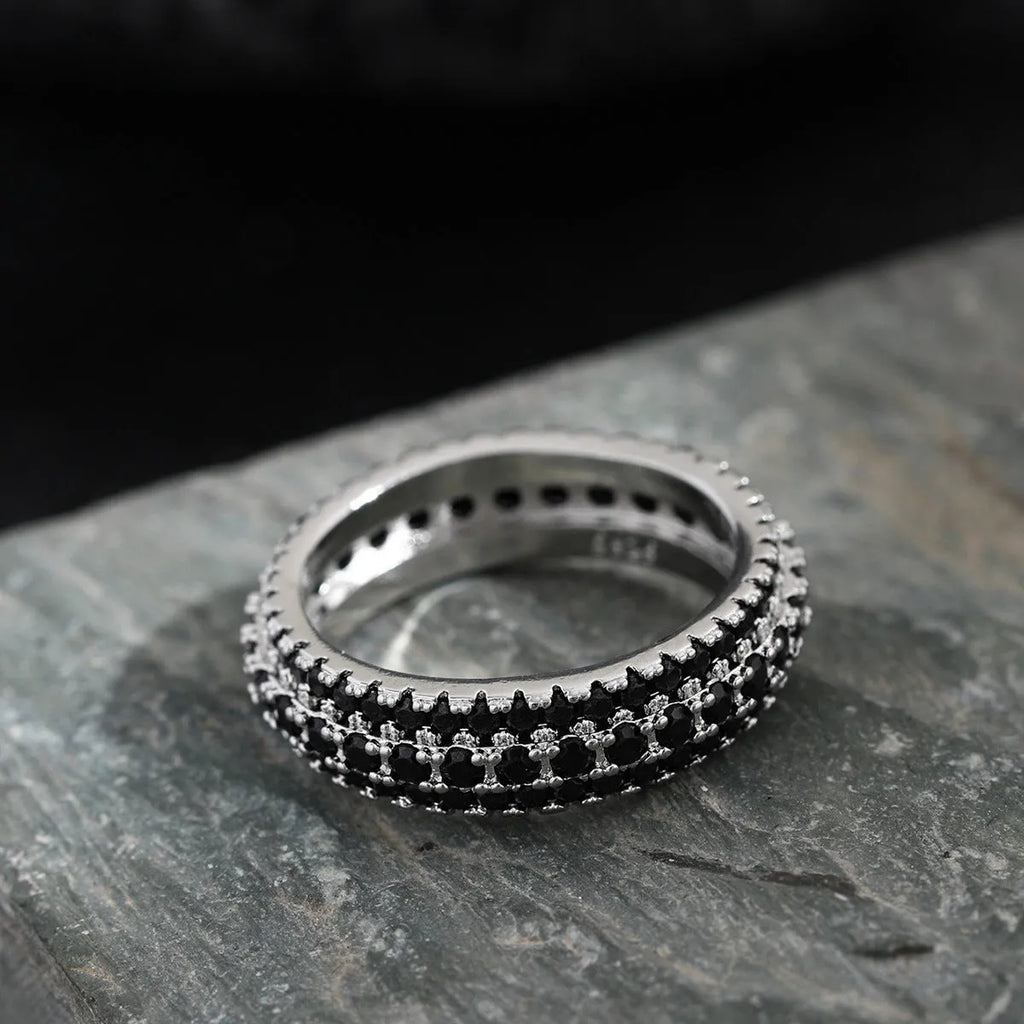 Geometric triangular zircon inlay ring in white gold finish on a finger.