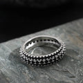 Geometric triangular zircon inlay ring in white gold finish on a finger.