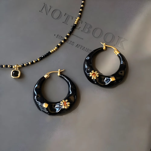 A pair of retro alloy ear studs with a dripping oil finish and black rhinestone detail.