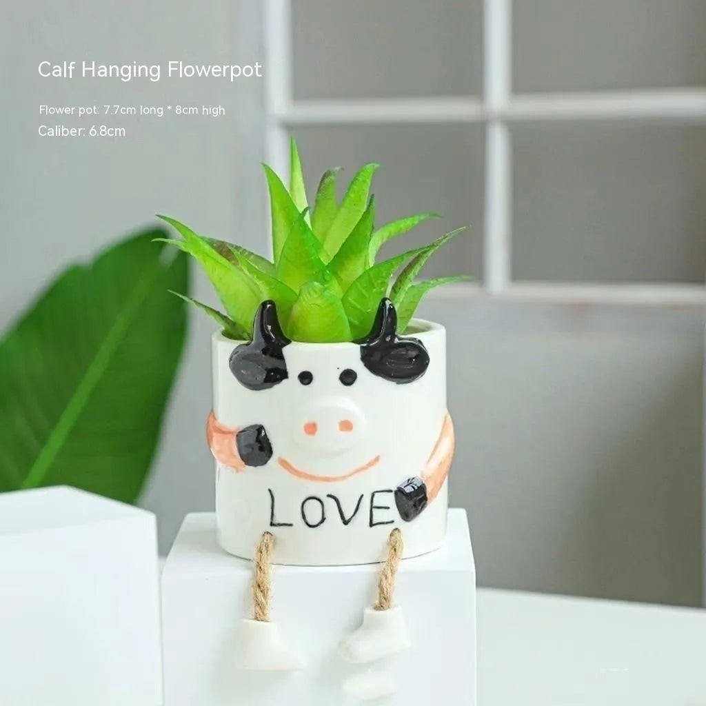 Ceramic hanging foot flowerpot in a cartoon style, shown on a desktop with a small succulent plant.