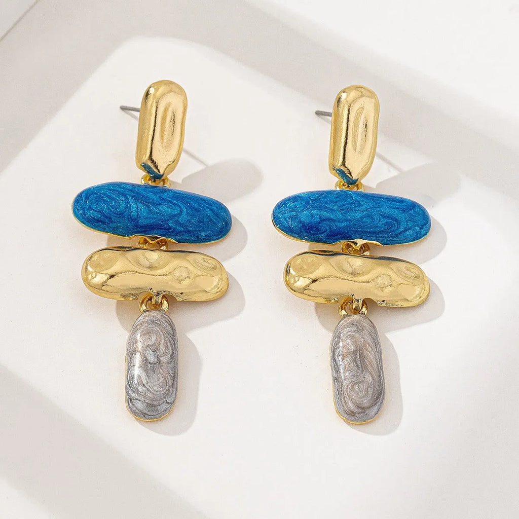 A pair of geometric-shaped stud earrings with a multicolour metallic finish on a plain background.