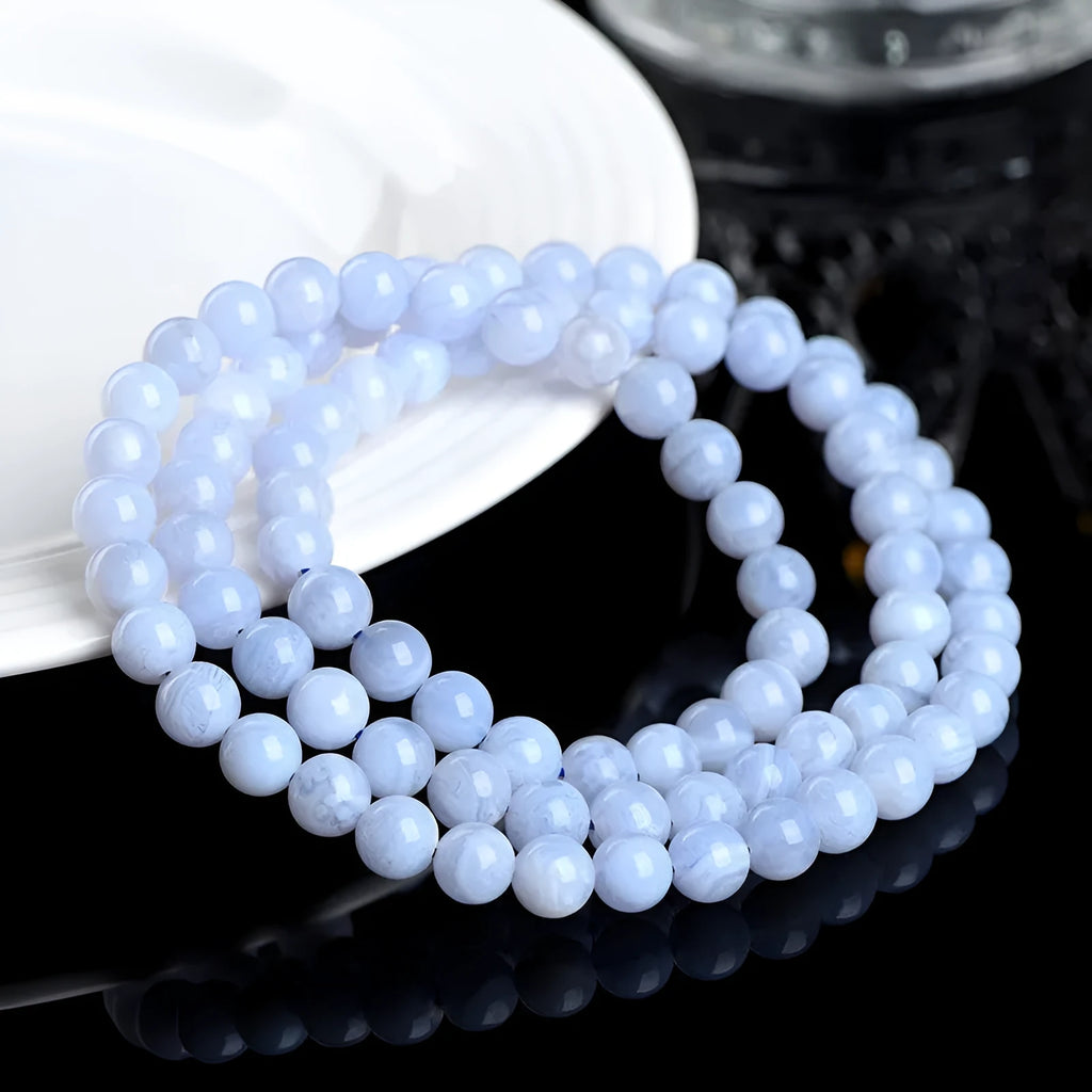 Close-up of a blue agate bracelet with scattered beads and striped spheres on a wrist.