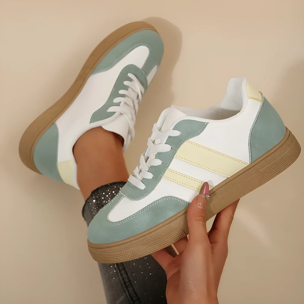 Green women's retro low-top trainers with cross-strap detail and round toe on a white background.
