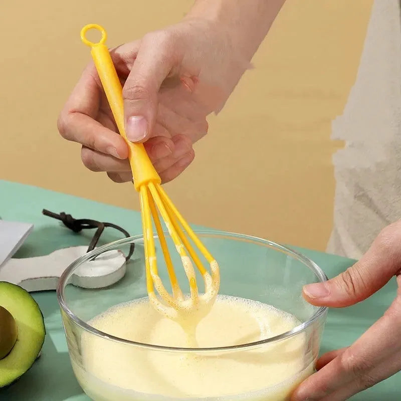 Plastic mini manual eggbeater in green for stirring batter in a kitchen