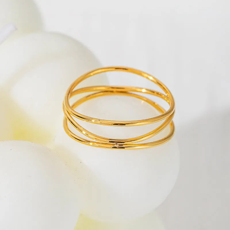 Gold geometric titanium steel coil ring showing three-layer bracelet-like design on a finger.