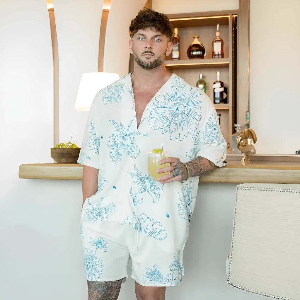 A man modelling a loose-fitting, short-sleeved beige cardigan with a printed floral pattern.