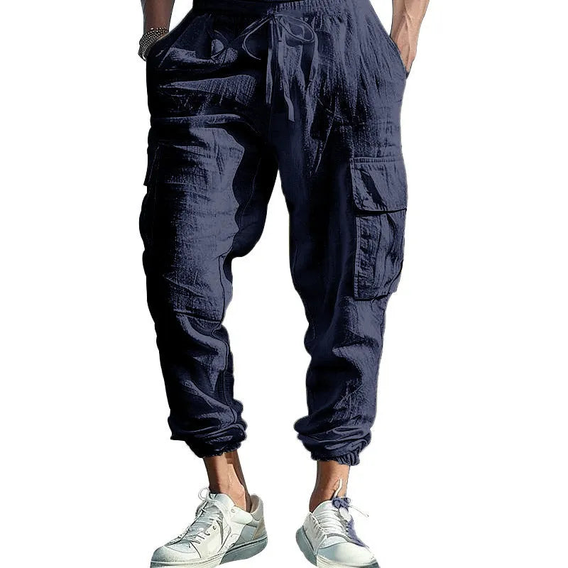 Man wearing loose khaki linen casual trousers with a drawstring waist and ankle-tied legs.