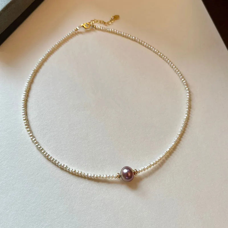 Pink purple freshwater pearl pendant necklace with U-shaped geometric design on a woman