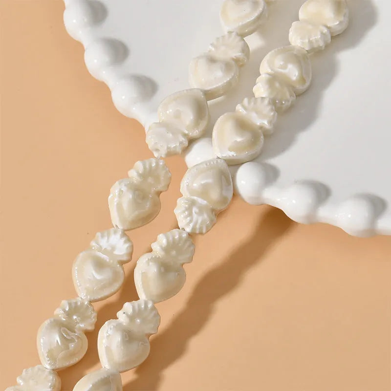 Small heart-shaped ceramic beads in multiple colours showing straight hole, approximately 10mm by 15mm size
