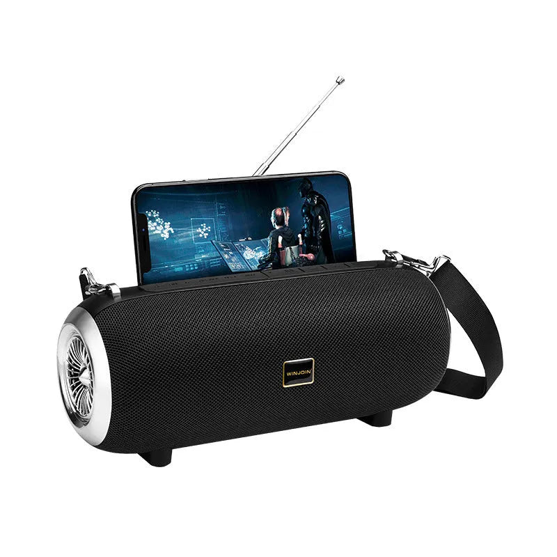 F666 portable fabric Bluetooth speaker with shoulder strap on a table next to a phone