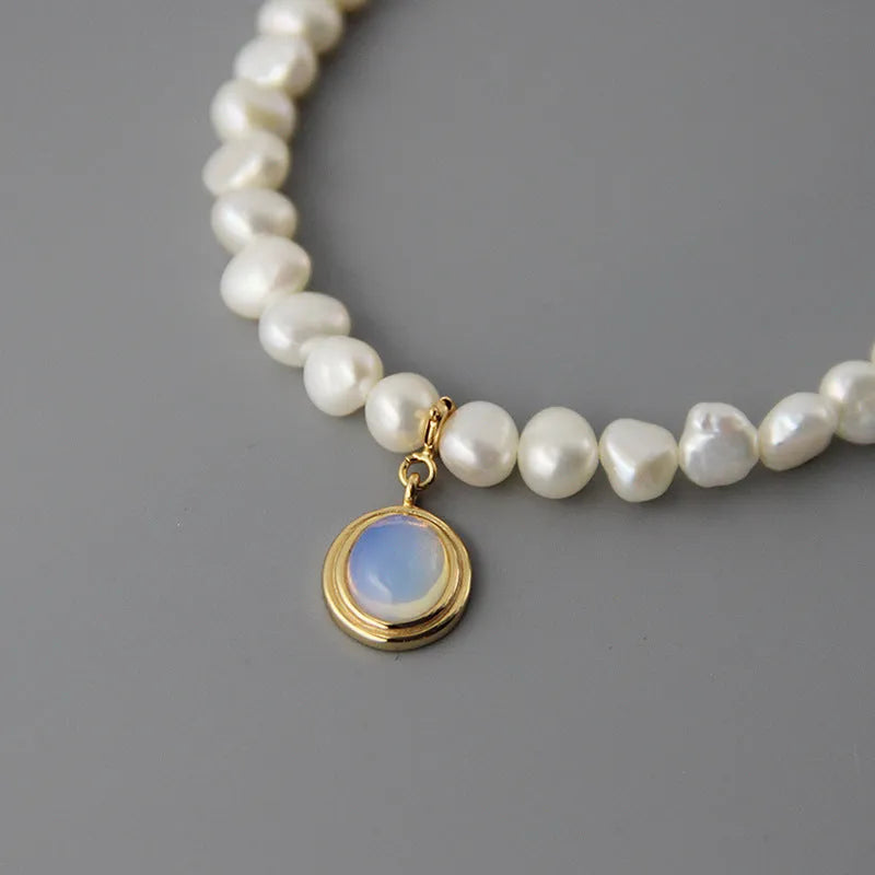 Round geometric sterling silver necklace with an irregular white pearl pendant on a chain.