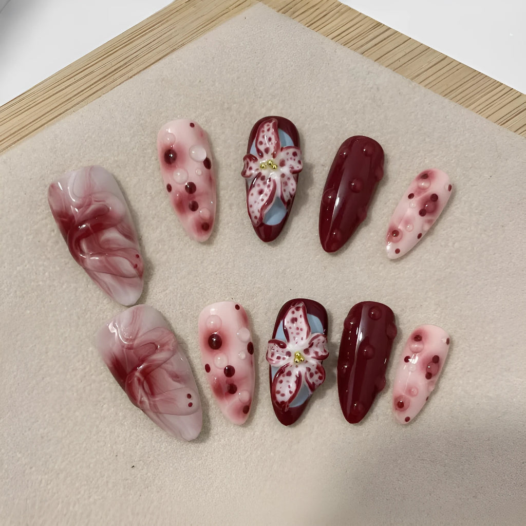 Hand-painted 3D carved press-on nails in mid-length almond shape with floral and pattern designs.