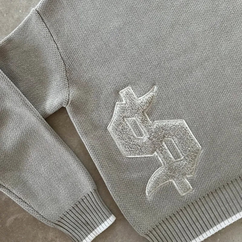 Grey loose-fitting long sleeve knitwear coat on a hanger.