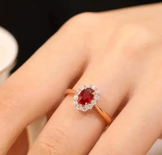 Silver plated ring with gold pigeon design and red blood gemstone inlay on a floral pattern band.