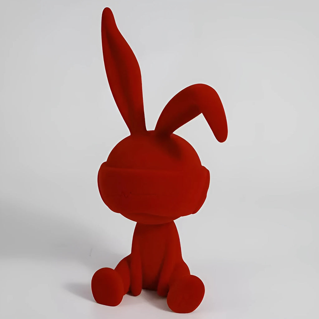 Green resin rabbit table ornament with a suede blindfold on a wooden shelf.