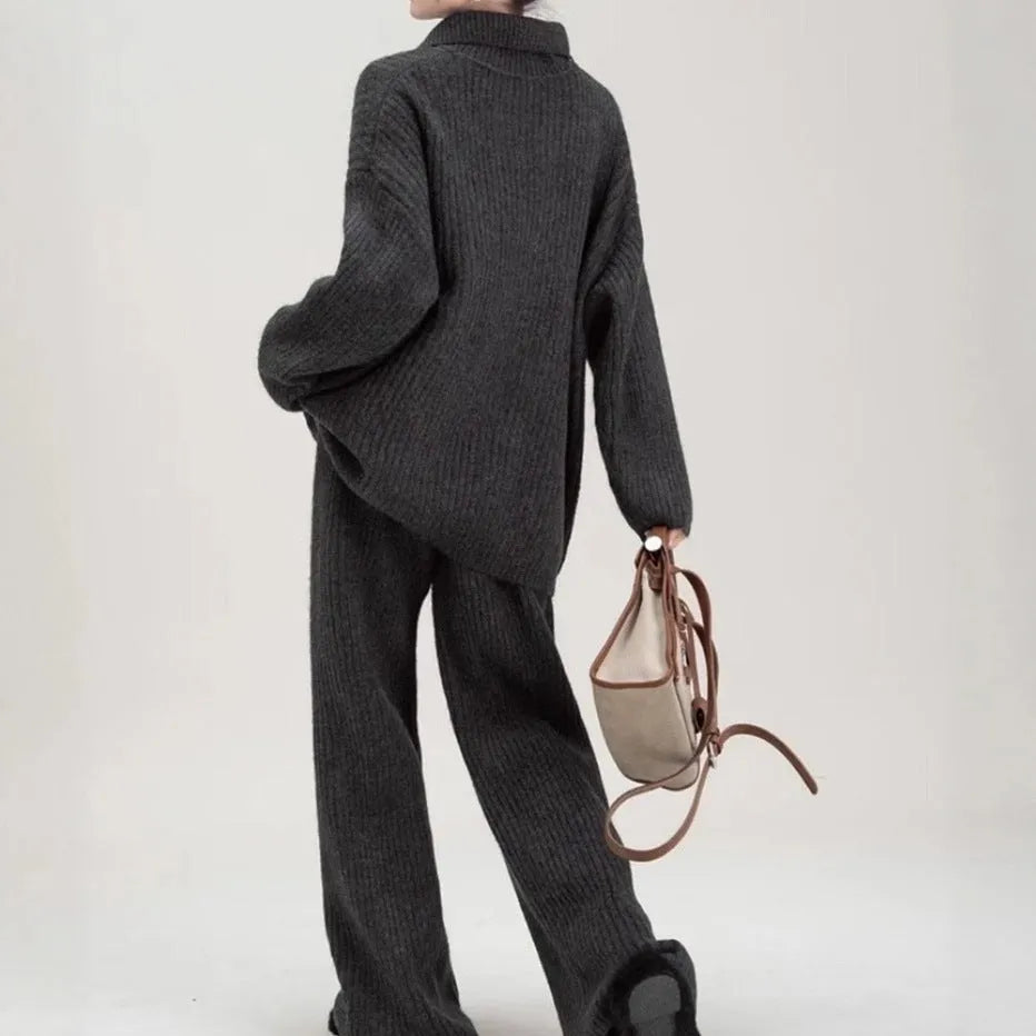 Women's beige knitted top and matching trousers from a two-piece acrylic sweater suit set laid flat.