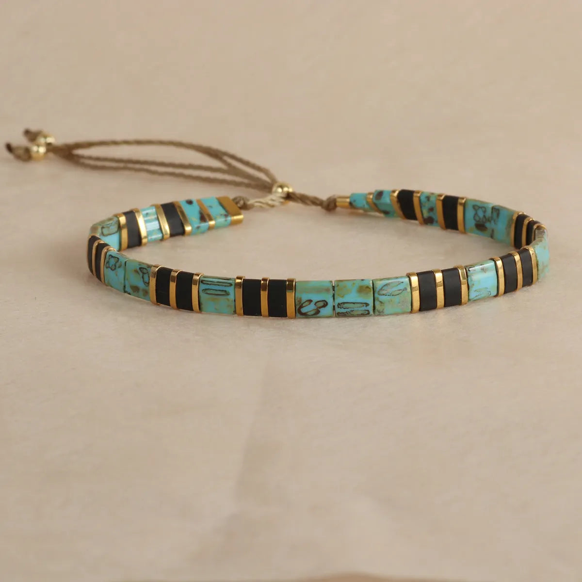 Adjustable geometric beaded bracelet with pull beads in milky white, black, green, blue or red.