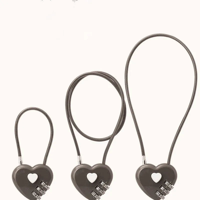 Peach heart shaped wire rope lock in multiple colours with a long steel cable, shown next to a bicycle helmet.
