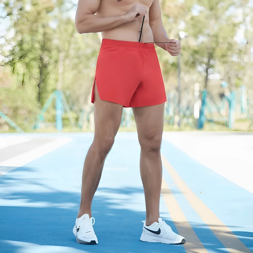 Men's red high-waist off-road running shorts with loose leg design, shown on a model running on a trail.