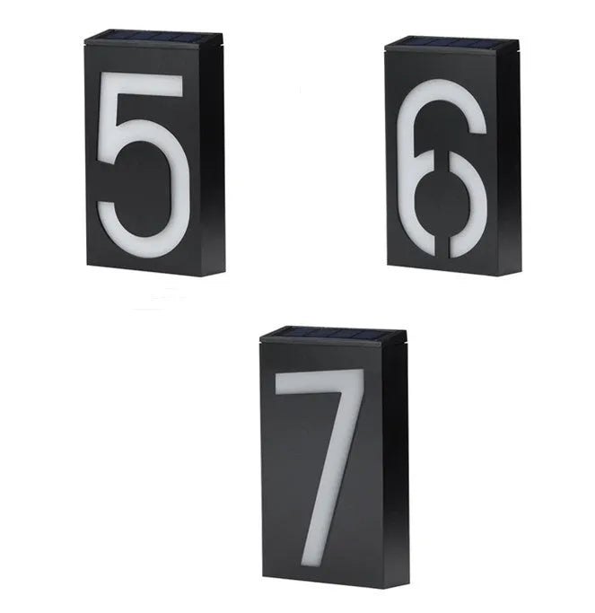 White solar powered illuminated house number sign with LED lights, mounted on a dark wall