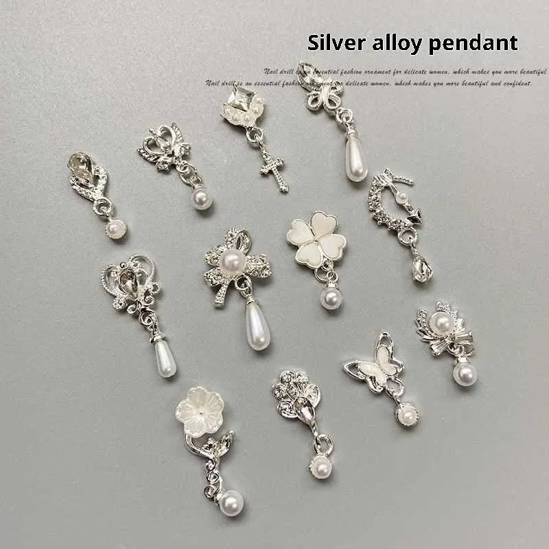 Mixed silver alloy metal nail art pendants with tassel and pearl accents on white background