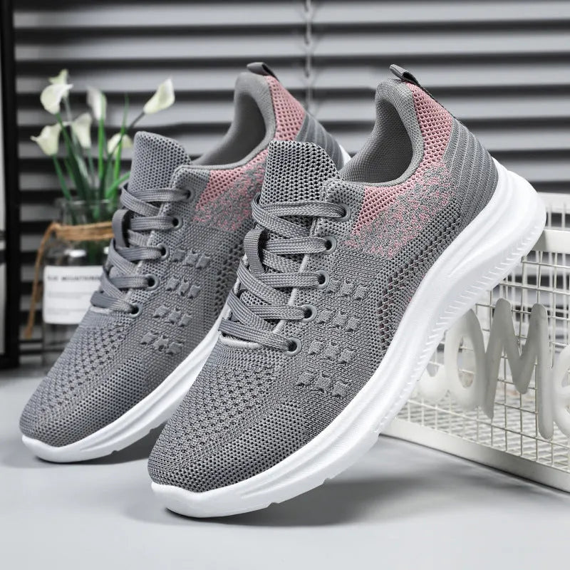 Women's black mesh low-top sneakers with round toe and white PVC sole on a neutral background.