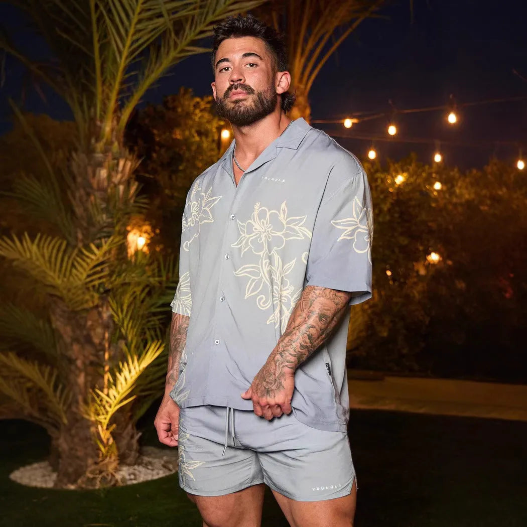 A man modelling a loose-fitting, short-sleeved beige cardigan with a printed floral pattern.