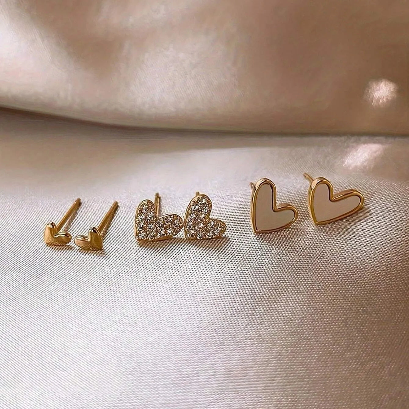 Three pairs of heart-shaped women's earrings in gold, black, and pink colour options