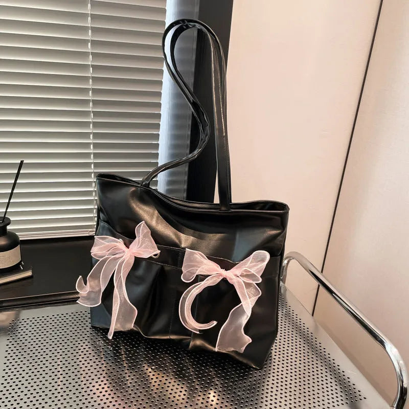 Black college-style tote bag with large capacity, a bow detail, and two shoulder straps.