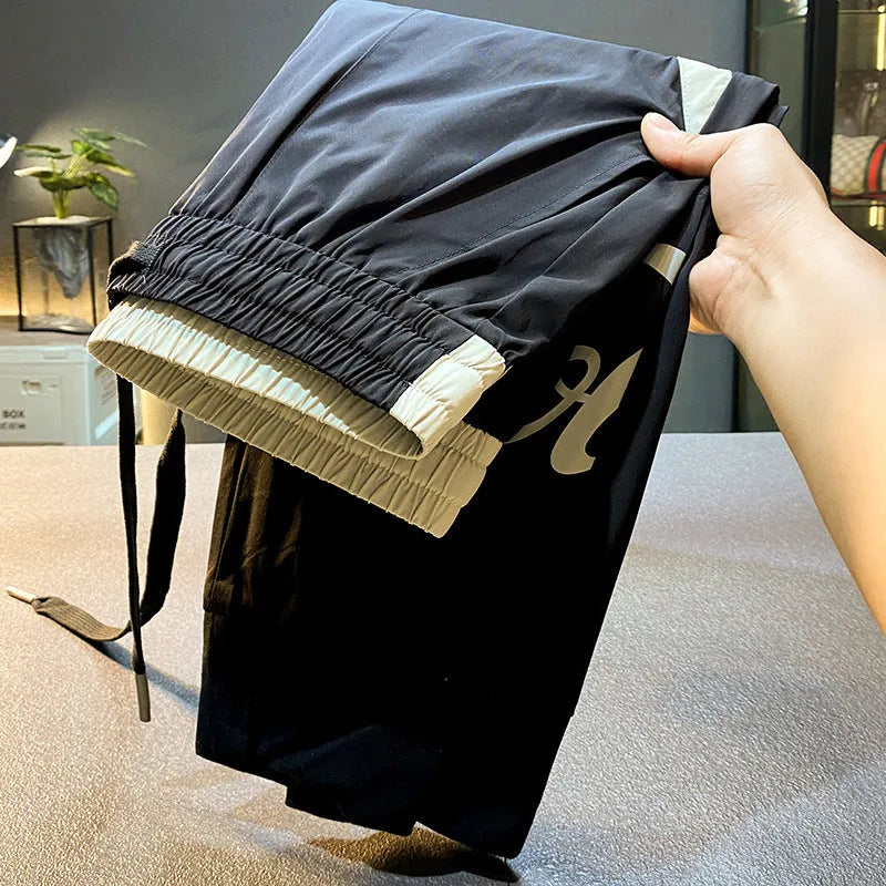 Man modelling black ultra-thin ice silk ankle banded casual cropped trousers.