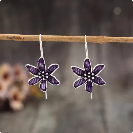 A pair of purple flower-shaped alloy drop earrings with a retro design on a white background.