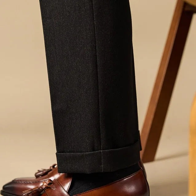 Men's black genuine leather tassel loafers on a solid background, showing polished upper and rubber sole.
