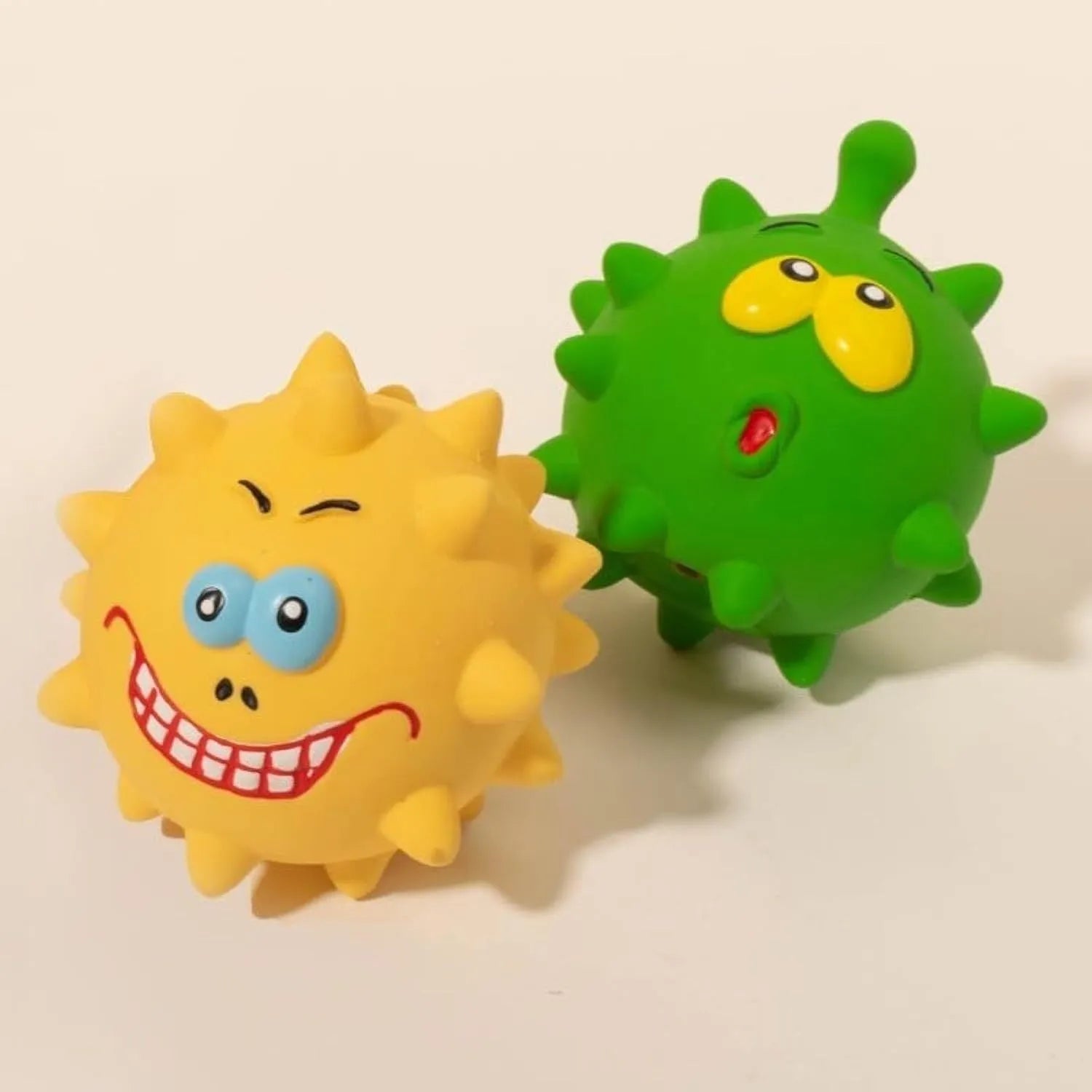 Set of four colourful squeaky dog balls with cute animal faces on a white background.