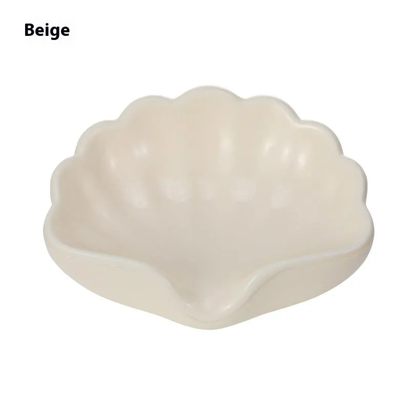 White shell-shaped plastic soap dish for bathroom use on a countertop.