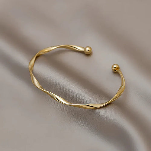 Gold alloy geometric twist bracelet with 6.2 cm inner ring diameter on white background