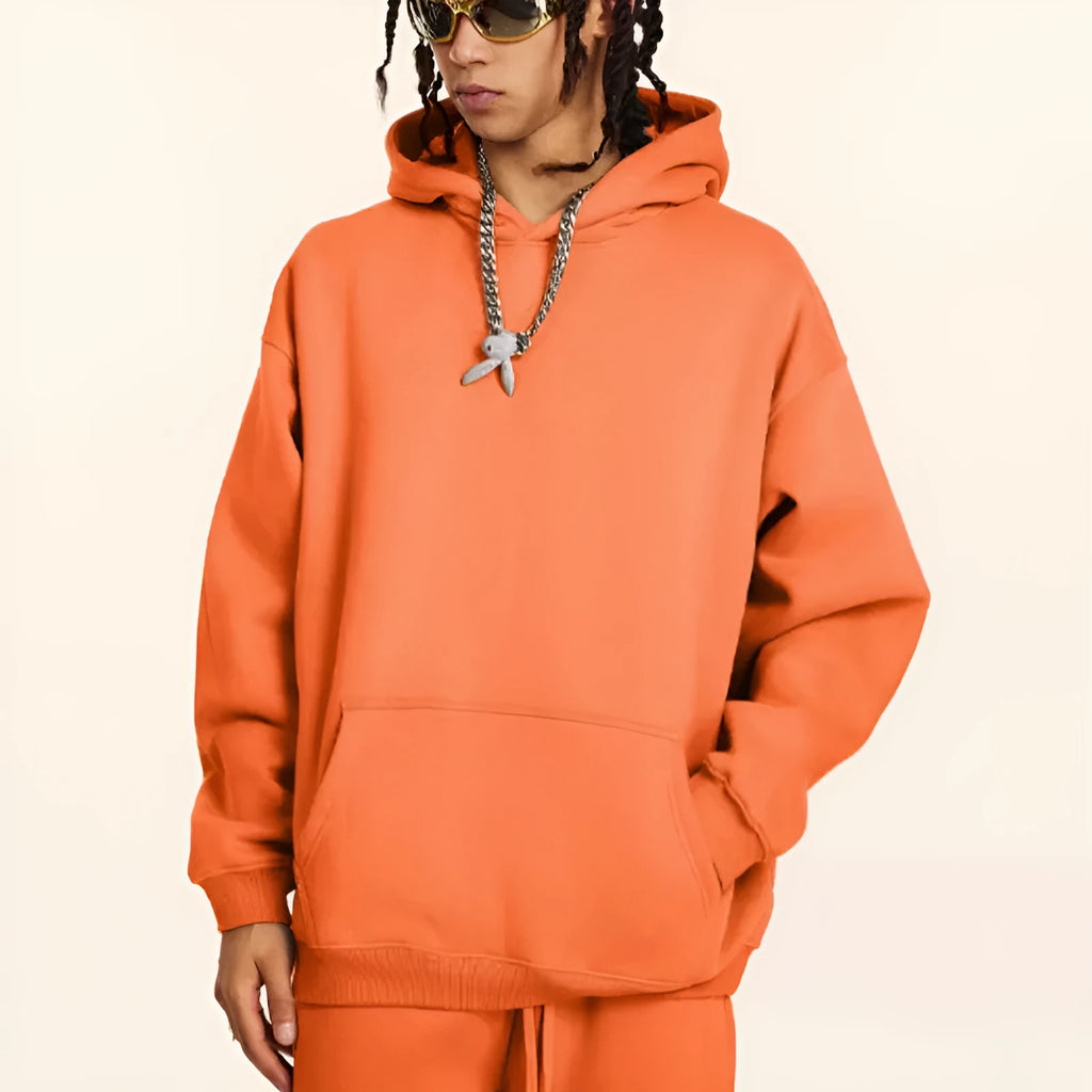 Man wearing a grey apricot loose-fit hooded sweater with drop-shoulder sleeves.