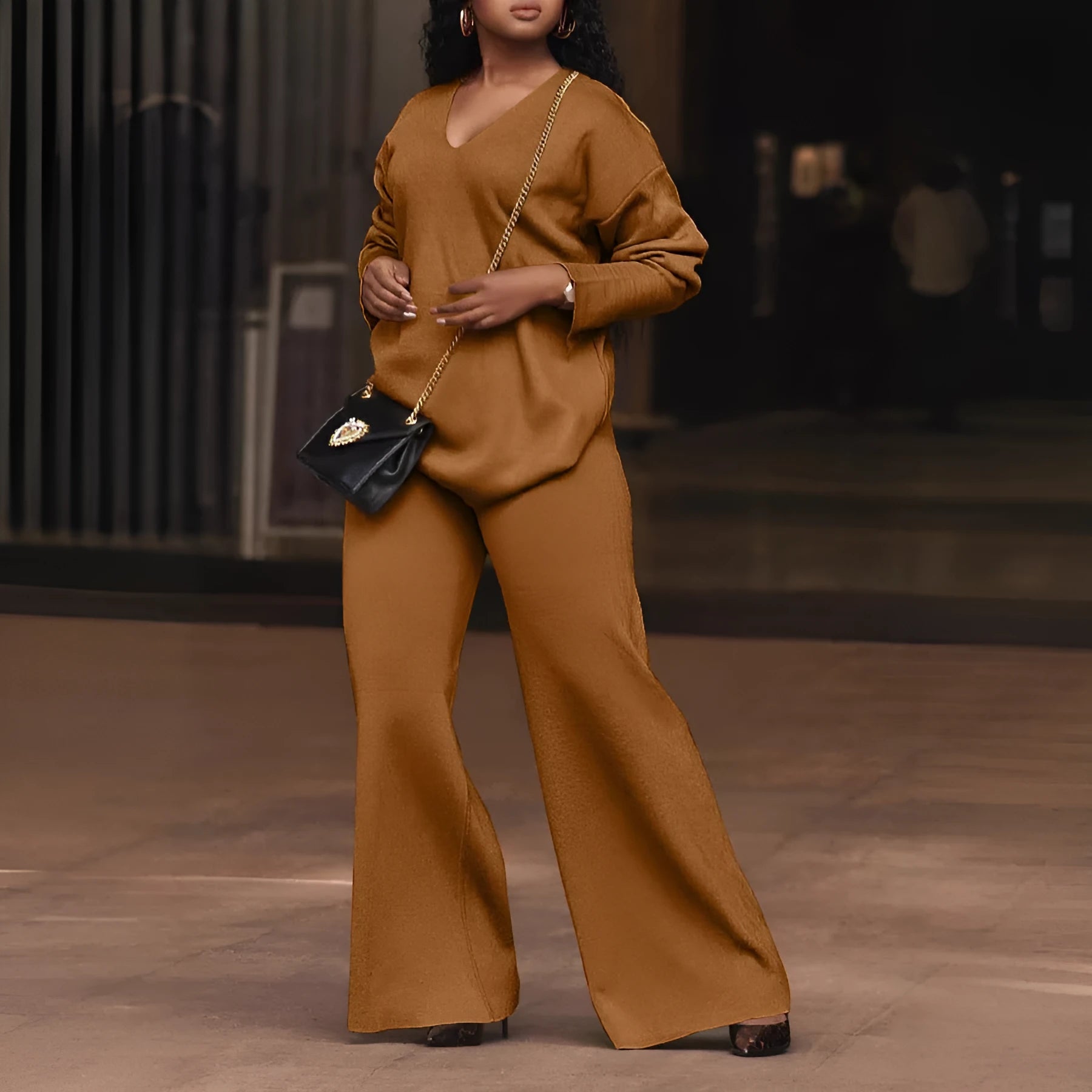 Brown women's suede two-piece suit with split sleeves and matching trousers on a hanger.