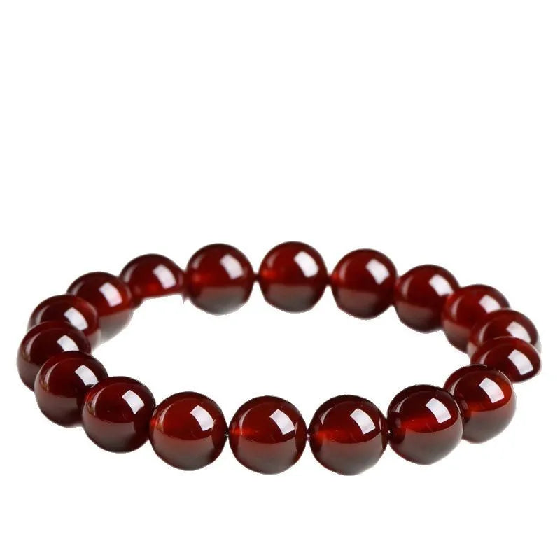 Natural orange red garnet crystal bracelet with Ruyi charms on a white background.
