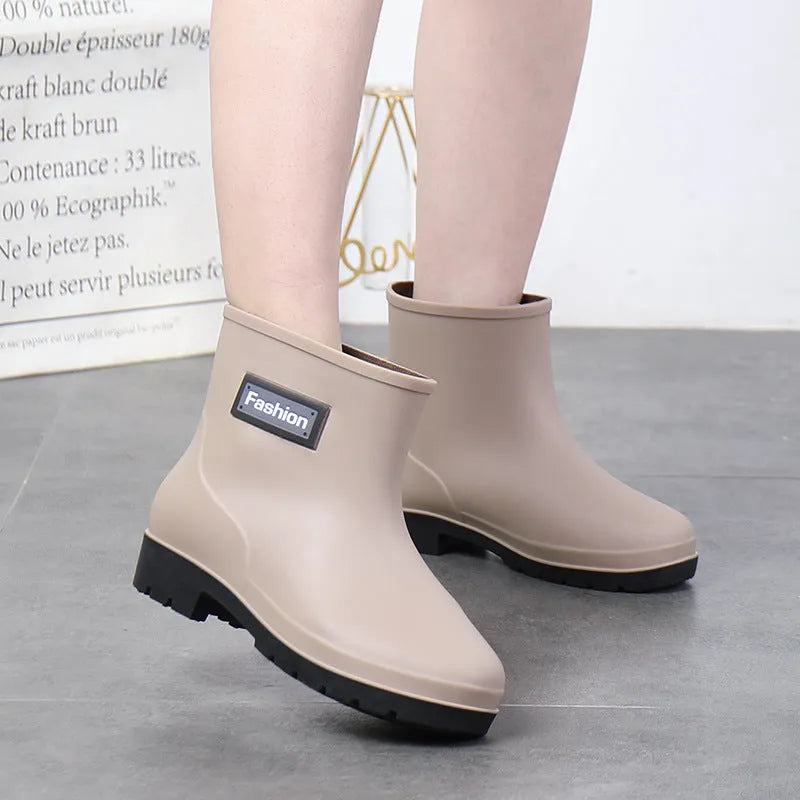 Women's black PVC mid-calf rain boot with a low heel on a wet surface.