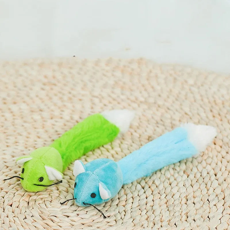 Three plush toy mice in green, pink, and blue with long tails, arranged on a surface