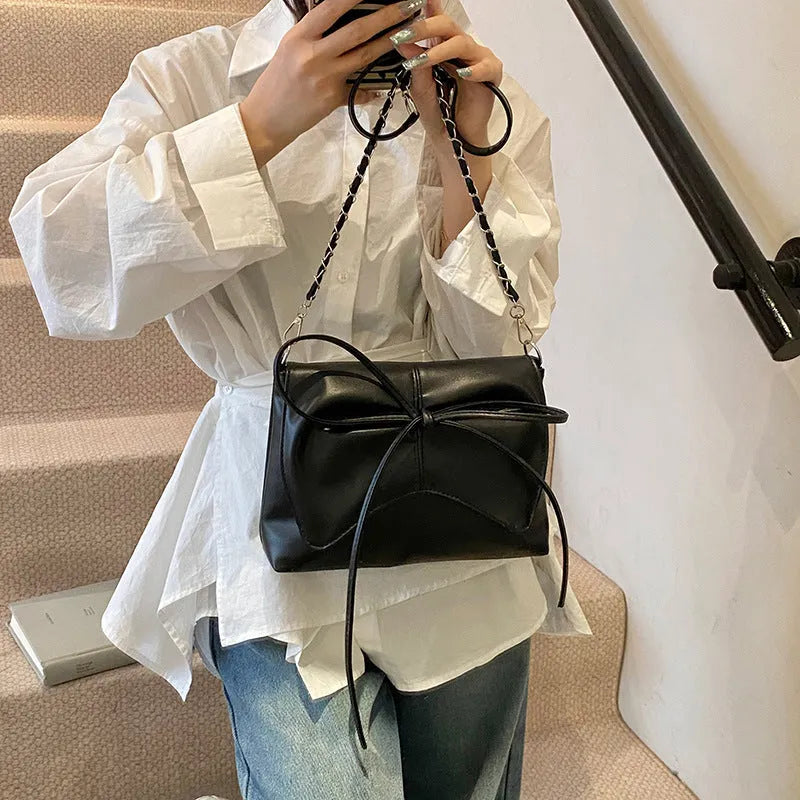 Women's black underarm crossbody bag with horizontal square shape and visible sewing details