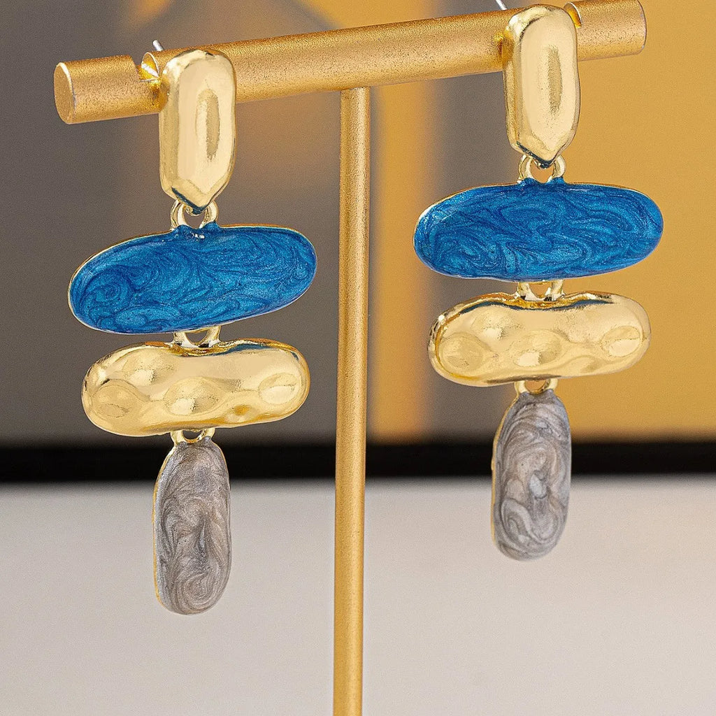 A pair of geometric-shaped stud earrings with a multicolour metallic finish on a plain background.