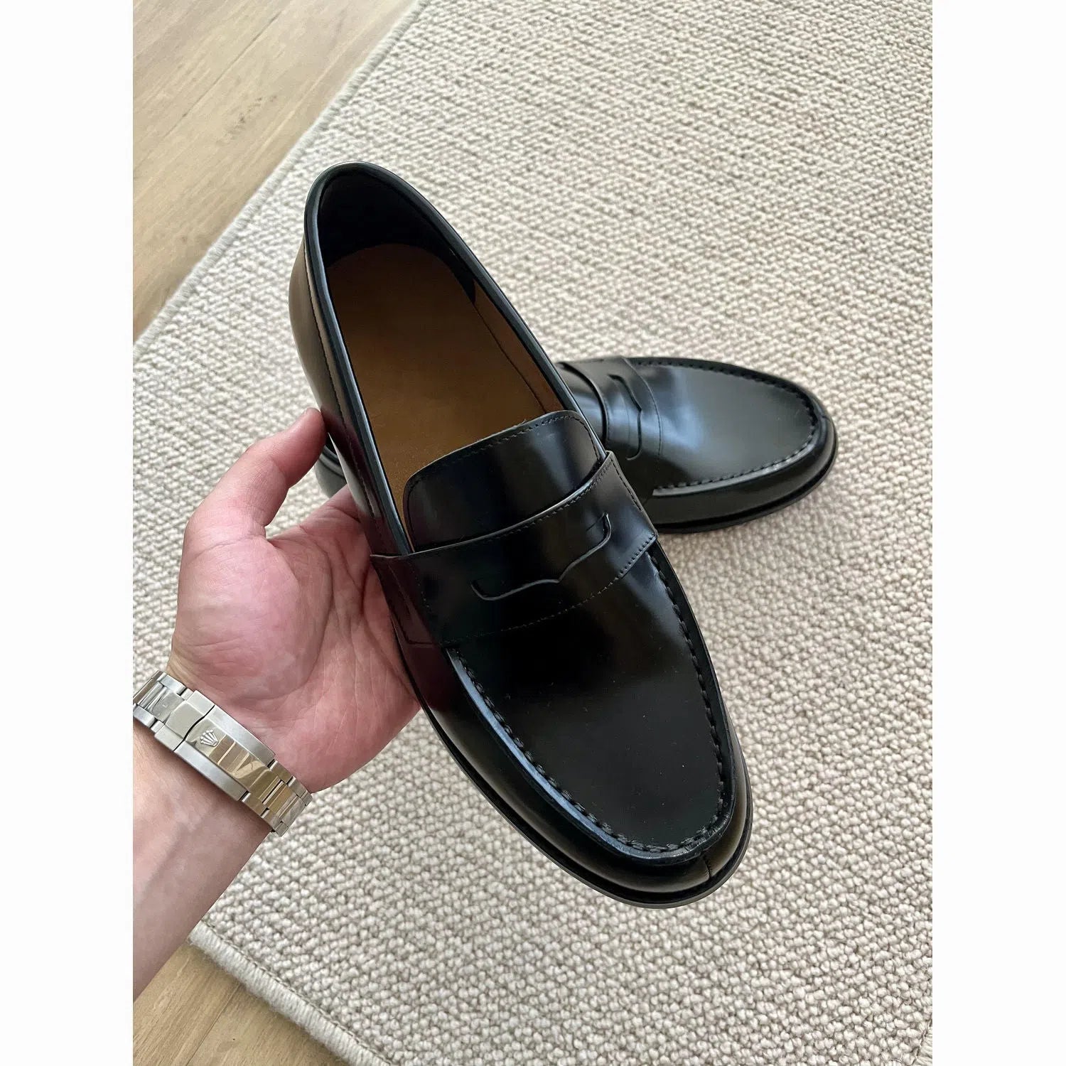 Men's black British-style slip-on leather loafers with stitched seams and vulcanised rubber sole on a plain background