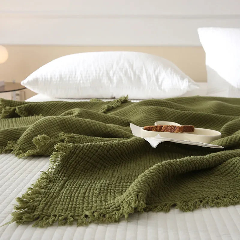 Four-layer gauze cotton blanket with tassel trim in navy blue colour, laid flat.