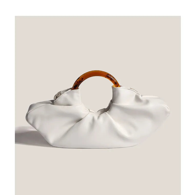 Niche horn bag in black or white PU leather with acrylic ring handle and fold detail for daily matching.